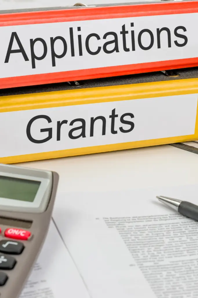 Carpetas de expedientes etiquetadas como "Grants" y "Applications" junto a una calculadora, representando la gestión de fondos externos.